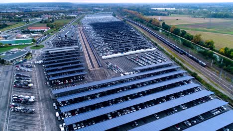 vista panorámica con un dron sobre un estacionamiento con paneles solares en francia. sólo hay coches en filas en un estacionamiento bajo los paneles solares, al lado del ferrocarril.