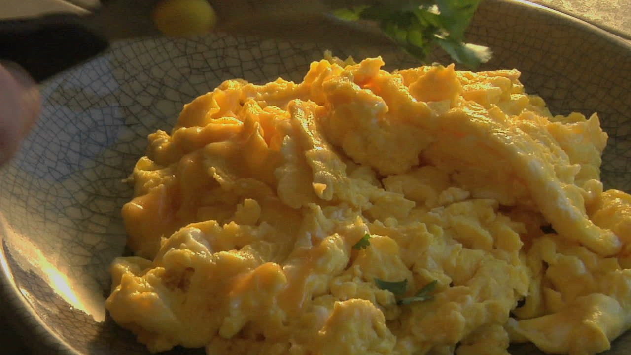 un tirón lento en un tazón de huevos revueltos mientras se corta el perejil