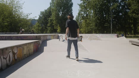 un chico caucásico caminando en el parque de skate.