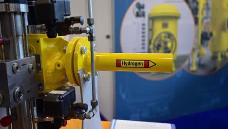 la palabra hidrógeno está escrita en un tubo amarillo que es parte de una demostración de válvulas de cierre especiales en una feria comercial, retroceder