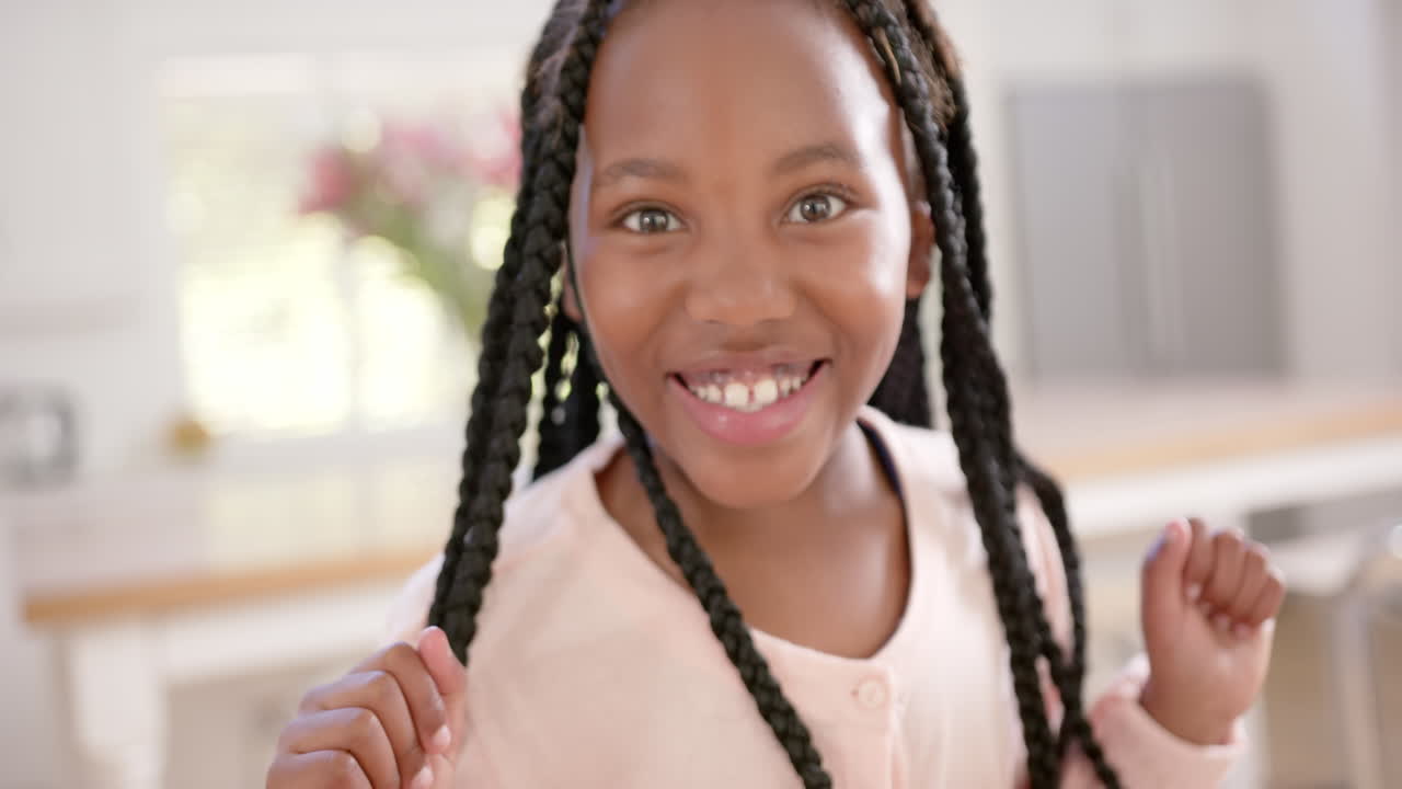 Ritratto di ragazza afroamericana felice con i capelli lunghi a casa, al rallentatore.