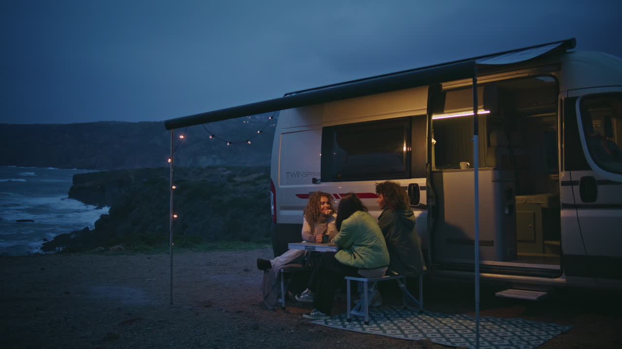 친절한 회사 저녁 해변에 휴식을 취하는 캠핑 테라스. 여자 이야기