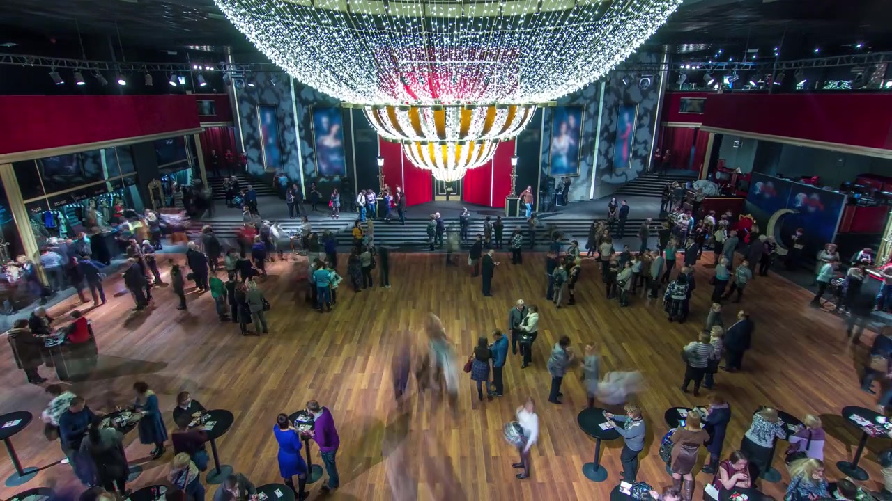 Timelapse of a beautiful and elegant parquet hall in a theater. People gather in the hall before the show, and there's movement toward the main stage entrance