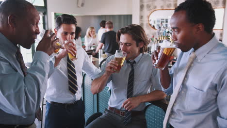 group of businessmen celebrating with drinks after work in bar