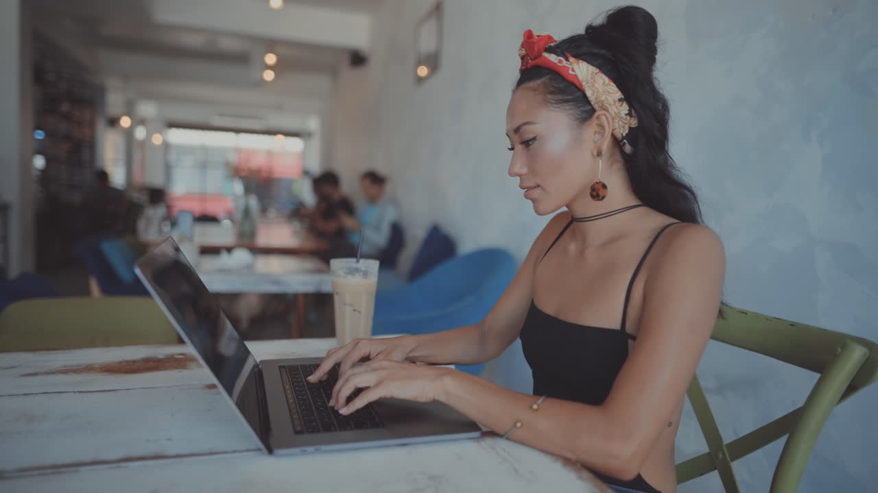Woman Working on Laptop in a Cafe