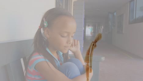 video compuesto de una estatuilla de madera contra una niña afroamericana estresada en el pasillo de la escuela