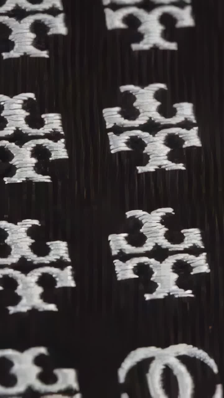 Vertical video: Panning camera down, revealing white motifs on black ribbed fabric for close view
