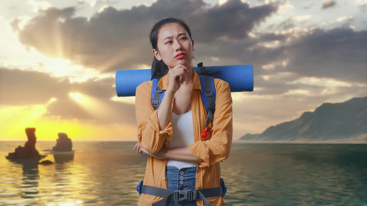 Pendaki Wanita Asia Dengan Ransel Gunung Memikirkan Sesuatu Dan Melihat Sekeliling Sambil Berdiri di Pantai Saat Matahari Terbenam