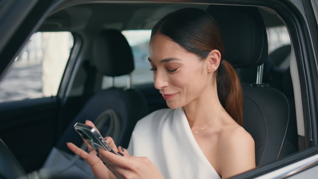chica elegante viendo las redes sociales en el teléfono inteligente en el asiento delantero del coche de cerca.