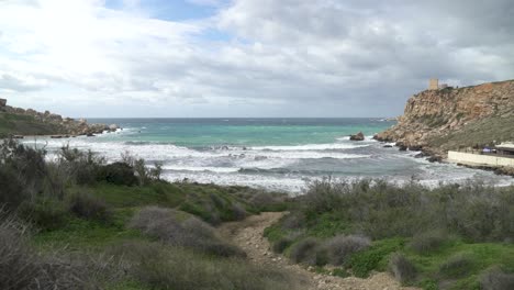 path leading to ghajn tuffieha bay with turquoise colour mediterranean sea raging in winter