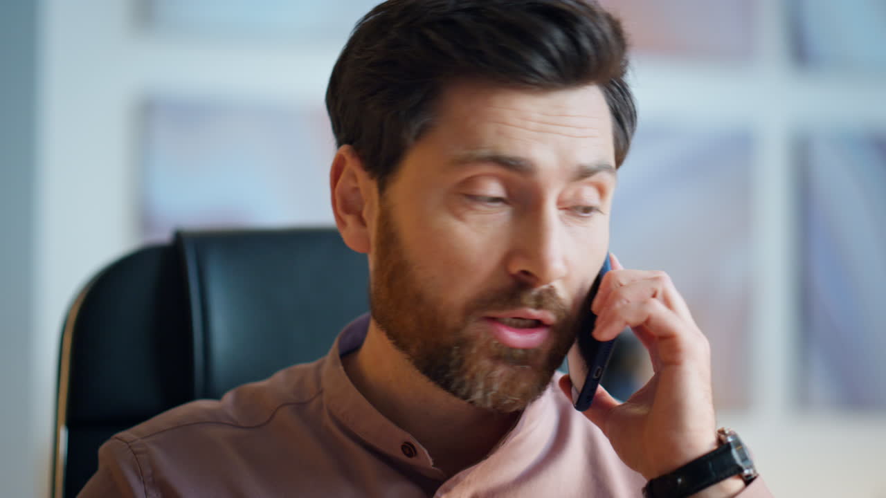 잘생긴 직원이 전화를 하고 앉아 있는 직장 근접 사진. 매니저가 전화를 하고 있다.