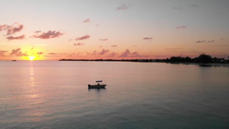 Langsam-Schwenkende-Drohnenaufnahme-Eines-Bootes-Im-Ozean-Bei-Sonnenuntergang