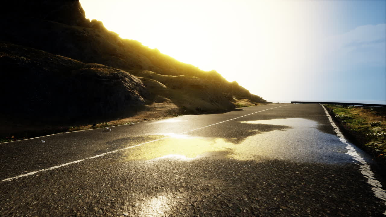 빛이 비치는 산악 풍경을 가로질러 비어있는 도로