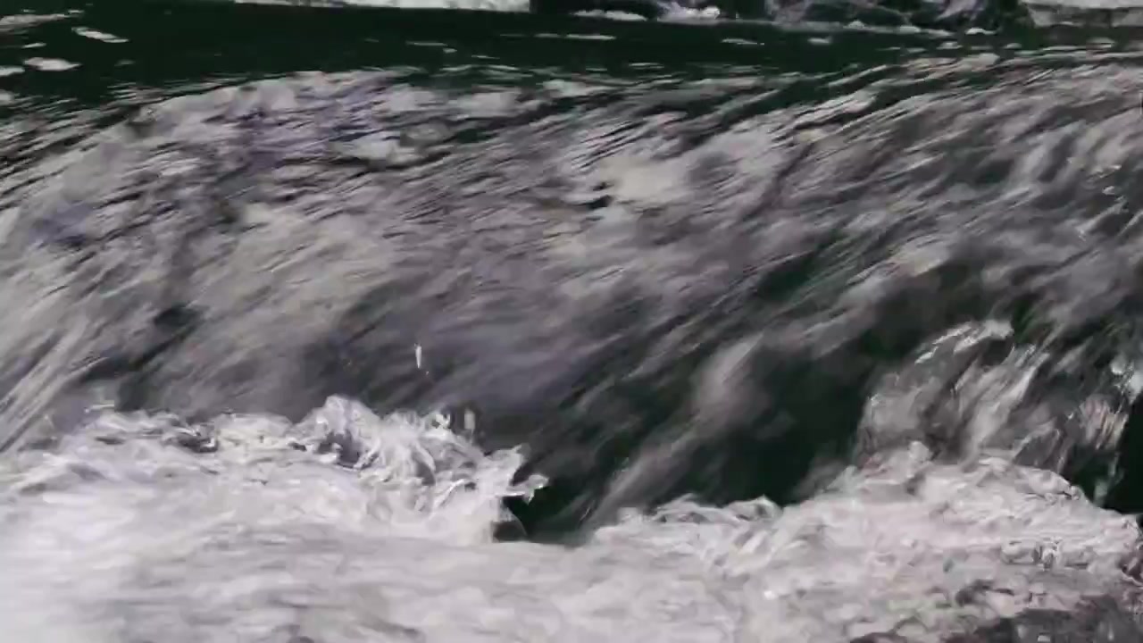 Nahaufnahme: Rauschendes Wasser fließt über Felsen in einem Bach
