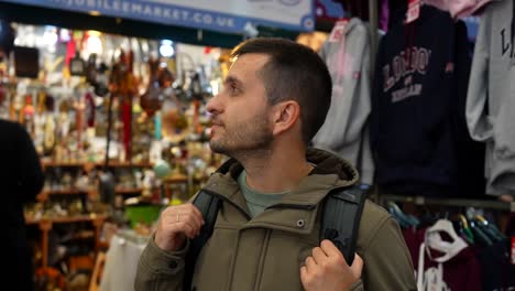 man explores jubilee market in covent garden with a backpack, surrounded by shops and souvenirs