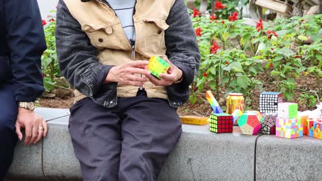 elderly man solving rubik's cube on street