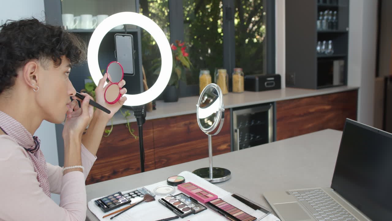 Applying makeup, person using smartphone and ring light in modern kitchen