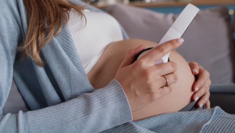 Pregnant-woman-holding-headphones-on-belly