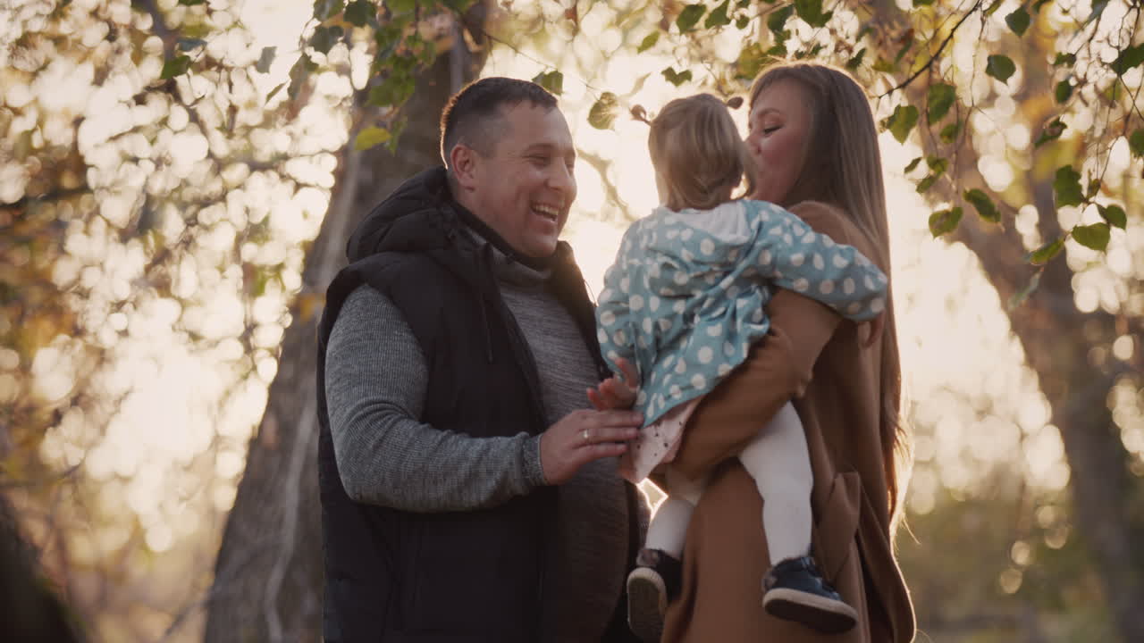 Famiglia felice con bambino si diverte in un parco autunnale.