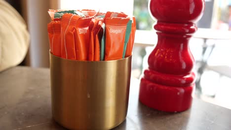sugar packets and pepper grinder on a table