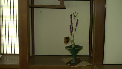 an ikebana flower arrangement on a shelf in a japanese house