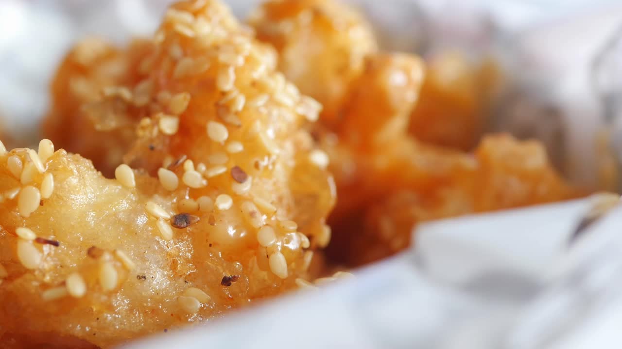 Nærbilde av deilig fritert kylling med sesamfrø og saus