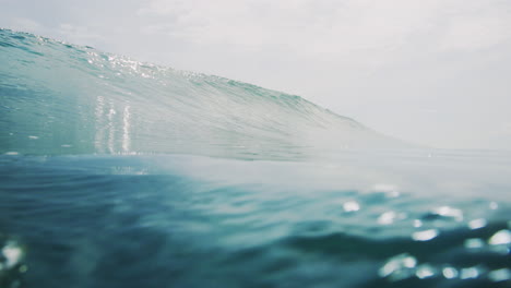 Wide-low-view-of-glistening-ocean-water-and-wave-crashing-on-surface