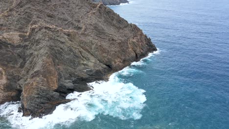 Aerial-view-of-Atlantic-ocean-waters-crashing-into-volcanic-rocks-at-the-cliff-steep-rocky-coastline-of-La-Gomera,-Canary-Islands,-Spain