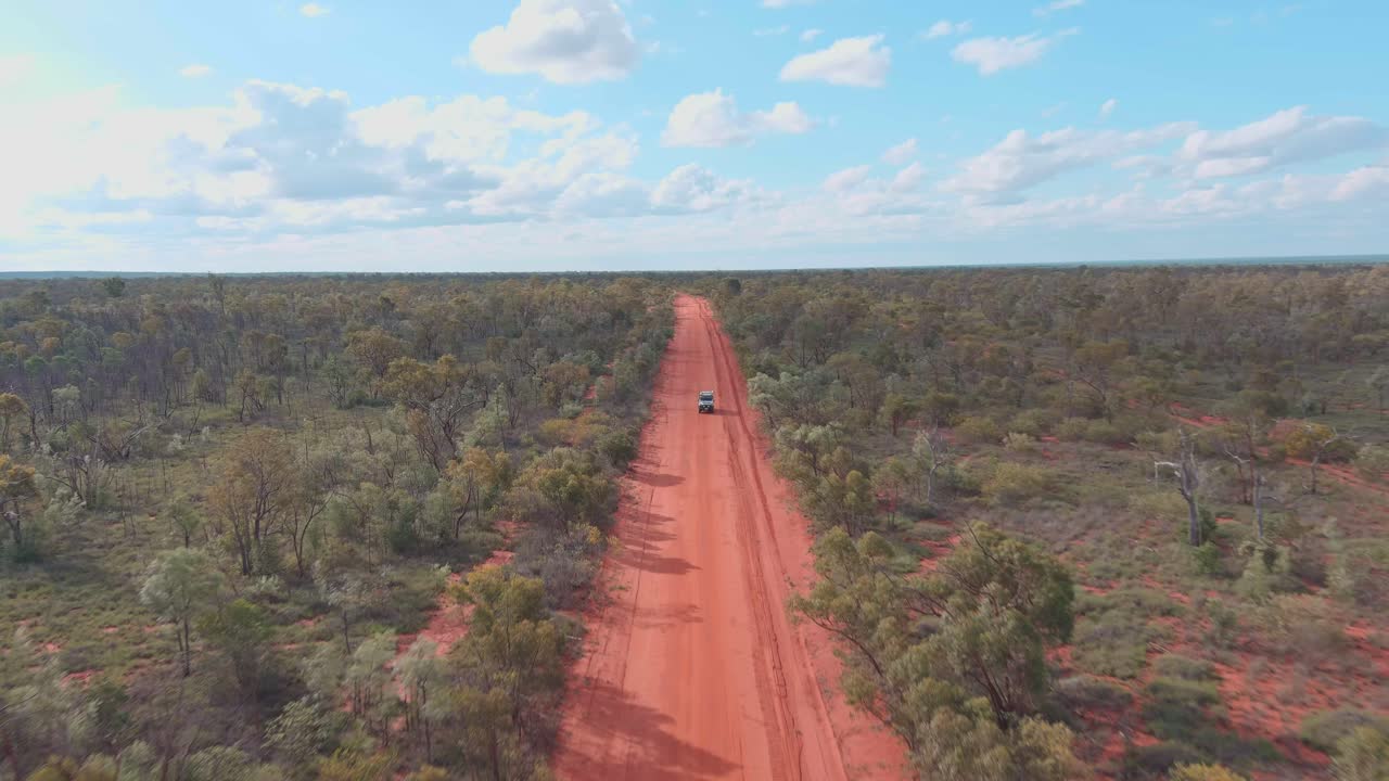 disparo de avión no tripulado, un coche conduce solo a lo largo de la carretera roja polvorienta del interior