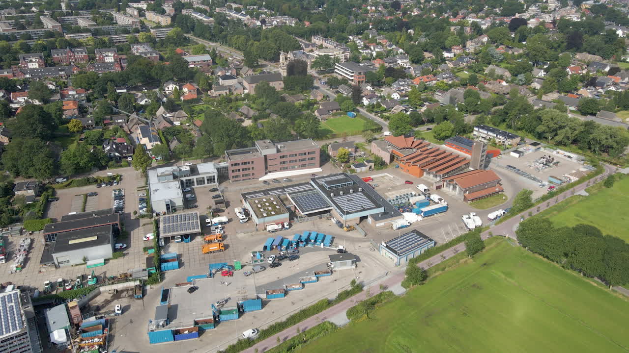 Højt luftfoto af biler, der kører ind og ud af en genbrugsstation.