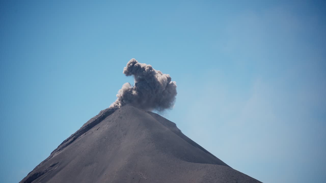 una erupción repentina al mediodía del volcán fuego, capturando nubes de ceniza contra un telón de fondo minimalista del cielo