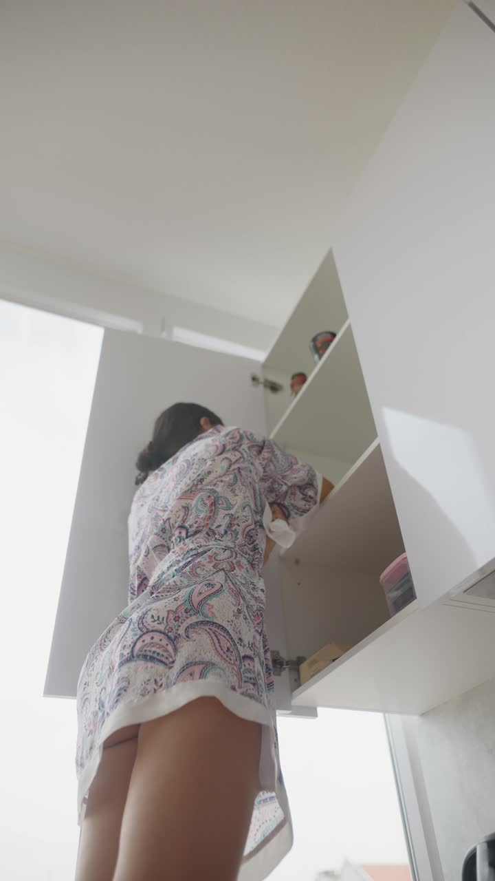 Woman Reaching into Kitchen Cabinets