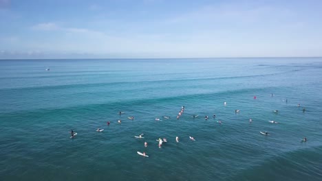 Hoard-of-surfers-compiled-on-the-pacific-ocean-in-waikiki-beach-honolulu-hawaii,-AERIAL-PULLBACK