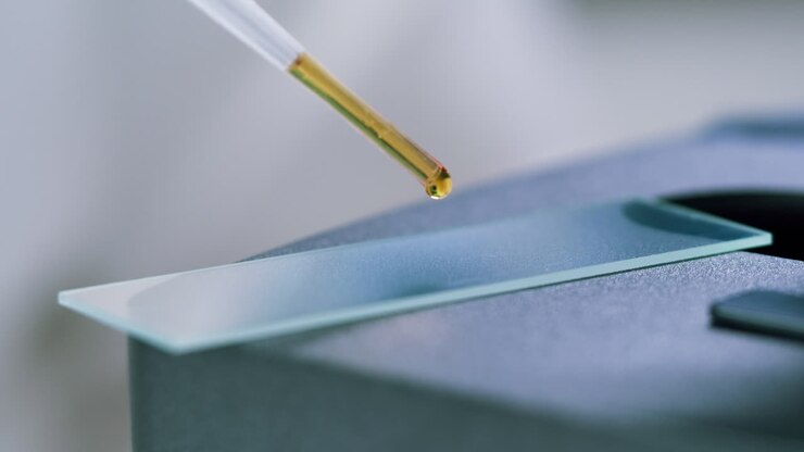 Pipette Dropping Yellow Liquid Sample onto a Microscope Slide