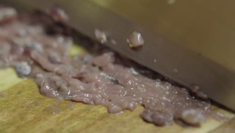primer plano de anchoas cortadas con un cuchillo en una tabla de cortar