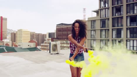 fashionable young woman on urban rooftop using a smoke grenade