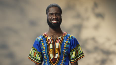 portrait of young cheerful african american man in traditional clothes smiling at camera