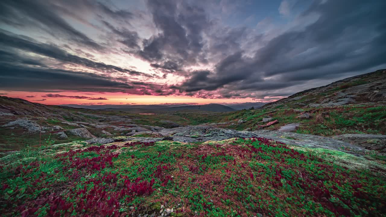nubes oscuras y tormentosas iluminadas por el sol rojo que se pone giran sobre el colorido paisaje de la tundra de otoño.