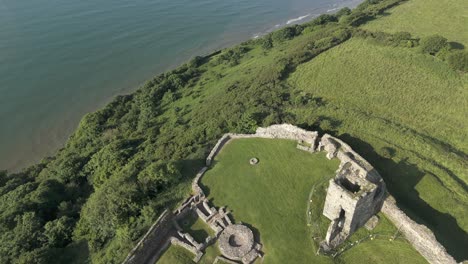 An-aerial-view-of-the-of-Llansteffan-Castle-in-Carmarthenshire,-South-Wales,-on-a-sunny-morning-with-a-clear-blue-sky