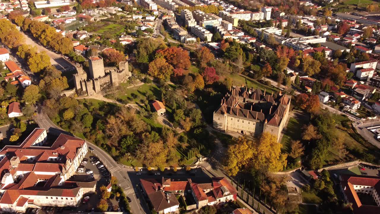 Luftzoom ind på middelalderslot og palads i skoven i Guimarães' gamle bydel i Portugal.