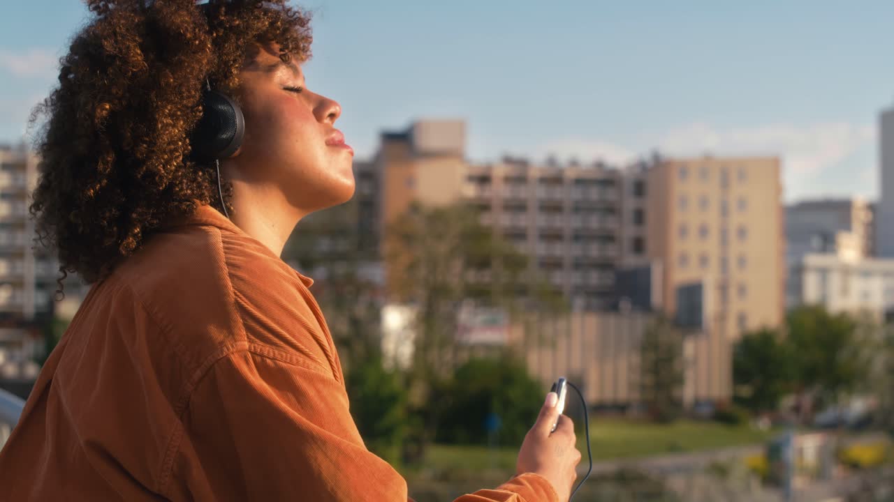 mujer negra con auriculares y de pie en el puente