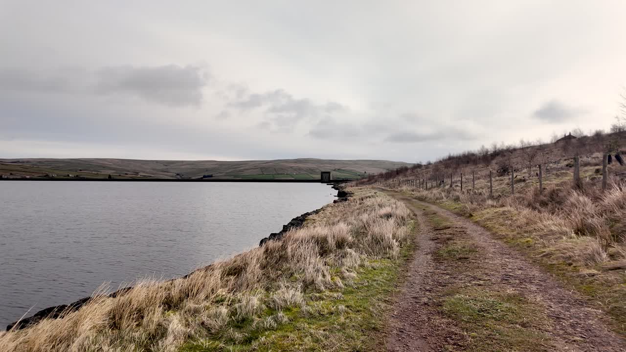 Burnhope reservoir and winding path across the rolling hills of County Durham. slow pan right shot
