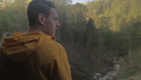 pan de un hombre caucásico disfrutando de la vista de una gran cascada desde el borde de un acantilado