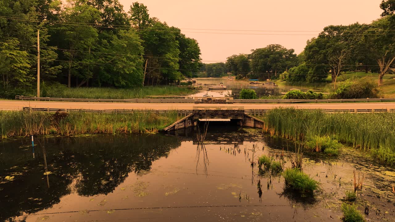 un puente de madera bajo, de estilo antiguo, que divide en dos un área de arroyo pantanoso