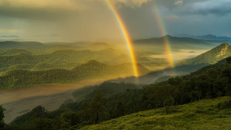 spectacular double rainbow over misty green mountains