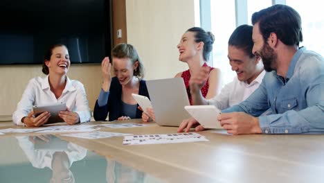 Smiling-business-team-interacting-with-each-other-in-conference-room