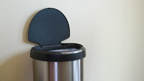 man throws away old vegetables in motion sensing touchless trash can - medium side