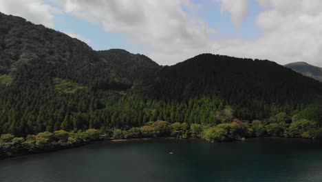 慢慢地向前移动的空中向孤独的渔船在湖上与美丽的绿色森林在背景