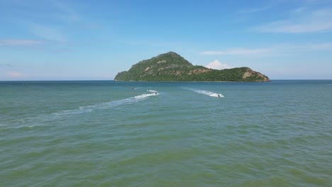 several jet skis moving, some going to the island, one rushing towards the shore