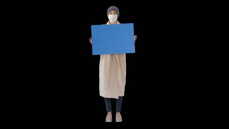 woman in outdoor clothes and in medical mask holding blank board, alpha channel